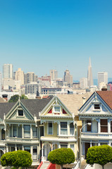 Bright blue sky view of San Francisco skyline viewed from Alamo Square with Victorian buildings in...