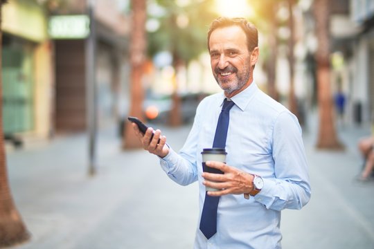 Middle age handsome businessman using smartphone drinking take away coffee smiling