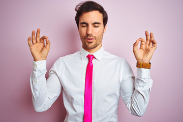 Young handsome businessman wearing shirt and tie standing over isolated pink background relax and smiling with eyes closed doing meditation gesture with fingers. Yoga concept.