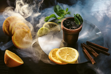 Tastes of hookah tobacco concept: citrus, lemon, mint, orange, cinnamon. Hookah and fruits on dark...