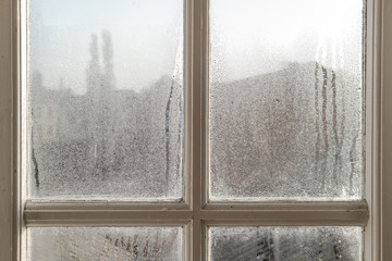 Interior of an old cottage, showing heavy water condensation on the interior windows during a winters morning. The wooden frames are visible.