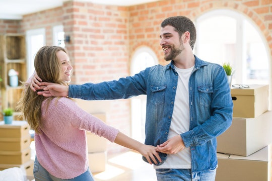 Young couple dancing celebrating moving to new apartment around cardboard boxes