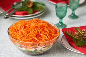 Layered vegetable salad with korean carrots in a glass bowl 