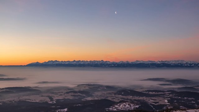 Sunrise over Tatra mountains seen from Babia mountain with cloud inversion and moon rising in the sky. Video with camera motion.