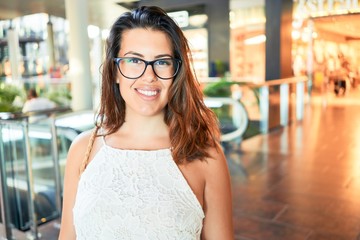 Young beautiful woman inside of shopping center, standing smiling happy and cheerful at the mall