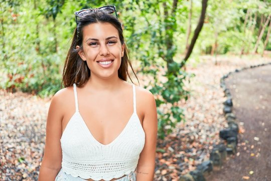 Young beatiful woman smiling happy and cheerful at green park on a sunny day of summer