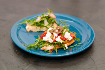 Bruschetta with shrimp, arugula, tomatoes, cheese and sauce. High Italian cuisine