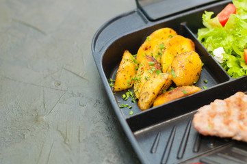 Lunch, grilled steak or meatball, salad with tomato potatoes on black plate. Concept healthy food, diet menus. Place for text with left, copy space.