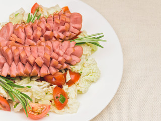 White plate with salad and sausages on the tablecloth. Creative serving for kids. How to cook tasty and creative sausages