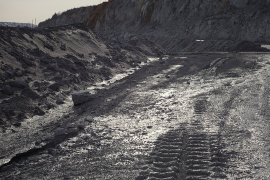 Traces of protectors of heavy quarry equipment on a dirty road in a quarry. Mining industry.