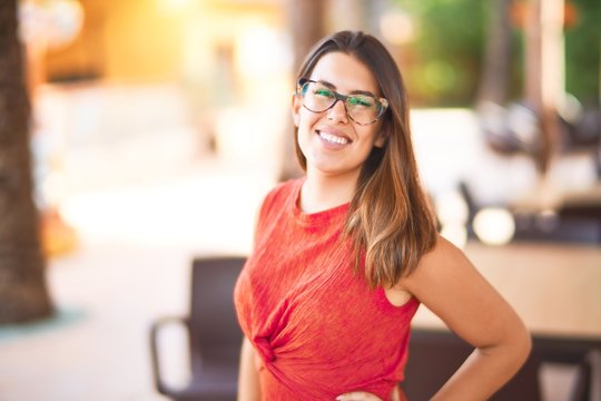 Young beautiful girl smiling happy and confident walking at the town park, standing with a smile on face