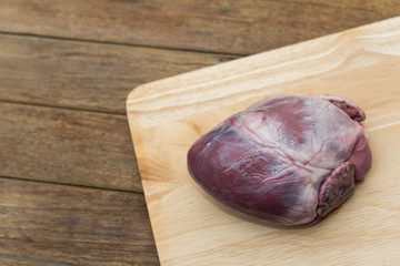 Fresh pig heart on wooden cutting board