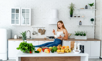 Healthy diet. Beautiful woman eating fresh organic vegetarian salad in modern kitchen. Healthy eating, food and lifestyle concept. Health, beauty, dieting concept.