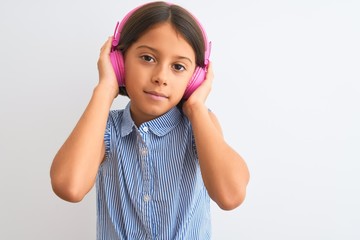 Obraz na płótnie Canvas Beautiful child girl listening to music using headphones over isolated white background with a confident expression on smart face thinking serious