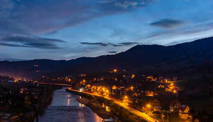 Night view of the village with residential houses and the road by the river.
