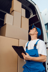 Deliveryman in uniform, parcels in the car, cargo