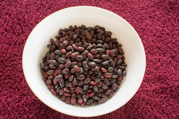 Red beans on a ceramic plate, seeds of annual garden bean plant with long narrow fruits