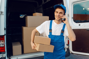 Deliveryman in uniform holds parcel and phone