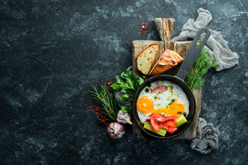 Breakfast. Fried eggs with bacon and vegetables in a frying pan. Top view. Free copy space.