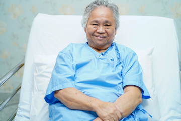 Asian senior or elderly old lady woman patient smile bright face while sitting on bed in nursing...