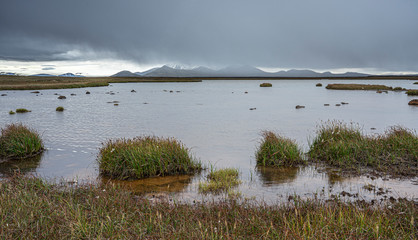 water and mountain landscape on a rainy day in Laugarfell Highland in Iceland