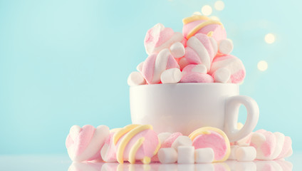 Marshmallow. Close-up of Marshmallows colorful chewy candies closeup, over blue background. Sweet food dessert in a cup with hot chocolate close-up. 