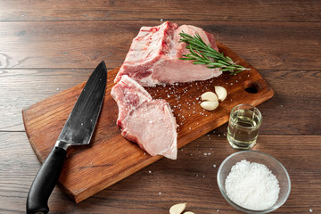 Fresh steak loin of raw meat and spices and a knife lies on a wooden background. copy space, flat...