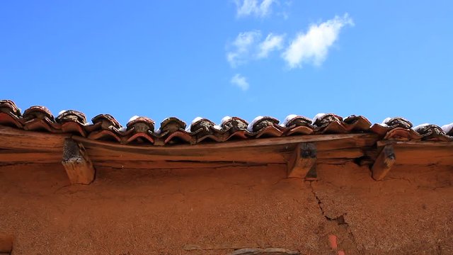Gotas de agua cayendo del alero del  tejado en el deshielo de la nieve en casa antigua de adobe