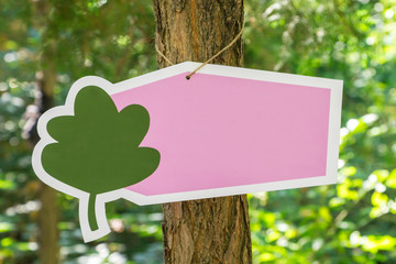 a blank banner tied to a tree, with pink blank space and painted by a tree on it, on a background of trees