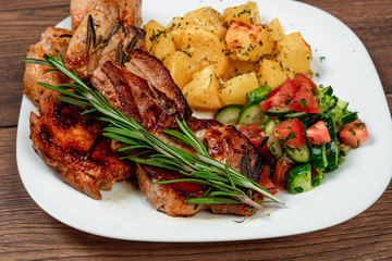 Pork steak, baked potatoes, salad and a sprig of rosemary. Recipe, cooking meat.