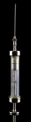 Naklejka premium Old metal syringe with glass liquid container on a black background