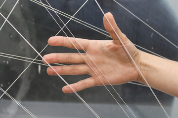 The girl's hand touches the white threads that cross each other diagonally