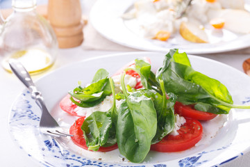 summer light lunch. Salad with spinach, cheese and tomato. Salad with pear and cheese. Salads are decorated on white plates