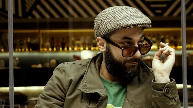 An obvious adult male adult flirter at a cafe checking out women.Stereotype of  European man winking at females passing by,taunting smiling and flirting in an apparent/blatant way.