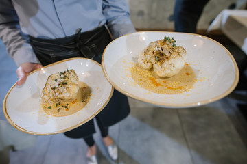 A waiter brings dish to clients at the restaurant