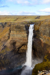 Tourist takes photo on mobile phone of second highest waterfall in Iceland - Haifoss. Picturesque sunrise view of deep canyon. Travel to Iceland. Beauty of nature concept background..