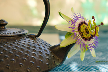 Obraz na płótnie Canvas Passiflora flower in the spout of a traditional Asian teapot. Fragment tea kettle.