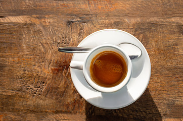 Top view Hot coffee in a white cup with saucer on a wooden table.