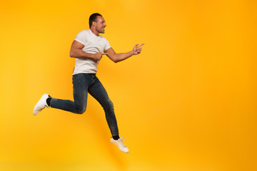 Sport man jumps on a yellow background. Happy and joyful expression.