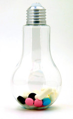 light bulb with multi-colored pills inside. On a white background, isolated. Medication leads to light and happiness
