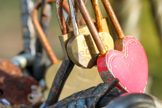 Wedding padlocks chained to the bench in city park. Symbol of love and old wedding tradition. Old rusty sweetheart locks. Horizontal picture of different colorful decorated metal locks with messages
