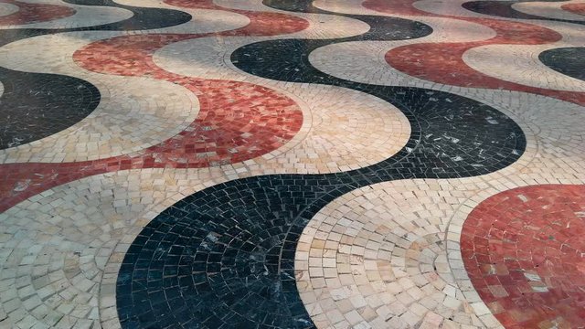 Detalle del Paseo de la Explanada en Alicante con su caracter&iacute;stico mosaico de teselas de colores  y pies de personas pasando 