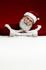 Portrait of classic Santa Claus smiling at camera while posing over blank white sign, copy space