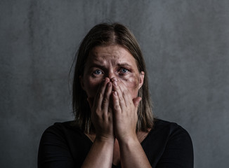 Scared young beaten up woman looking at camera and covered her mouth with her hands