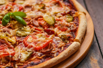 fresh baked pizza on brown wooden table close up