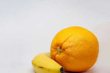 Fresh organic orange and banana close-up on a white background with place for text.