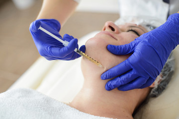 Needle mesotherapy in beauty spa salon or clinic. Cosmetics been injected to woman's face, close up...