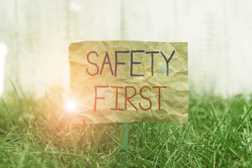 Word writing text Safety First. Business photo showcasing used to say that the most important thing is to be safe Crumpled paper attached to a stick and placed in the green grassy land
