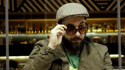 An obvious adult male adult flirter at a cafe checking out women.Stereotype of  European man winking at females passing by,taunting smiling and flirting in an apparent/blatant way.