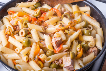 Italian cuisine - penne rigate pasta with tuna, olives and pepper sauce cooked in a pan